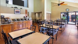 A spacious dining area with multiple tables and chairs, a kitchen area with a buffet, and a large window providing natural light. - Best Western Plus Redondo Beach Inn (Redondo Beach)