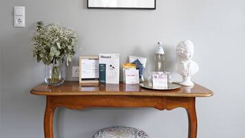 A wooden table with a vase of flowers, a framed picture, and some items on it.