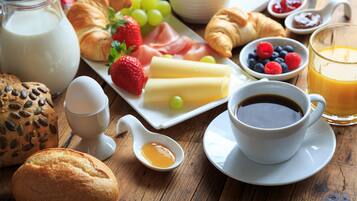 A breakfast setting with croissants, strawberries, cheese, and a cup of coffee on a wooden table.