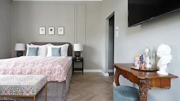 A bedroom with a bed, bedside tables, a TV, and a desk with a bust sculpture.