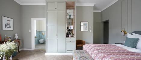 Un dormitorio con cama, cómoda, tocador y baño visible a través de una puerta abierta.