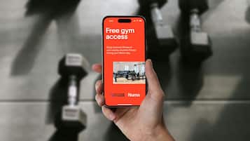 Une main tenant un smartphone affichant un message informant des clients Numad qu’ils peuvent accéder gratuitement à la salle de sport Anytime Fitness pendant leur séjour.