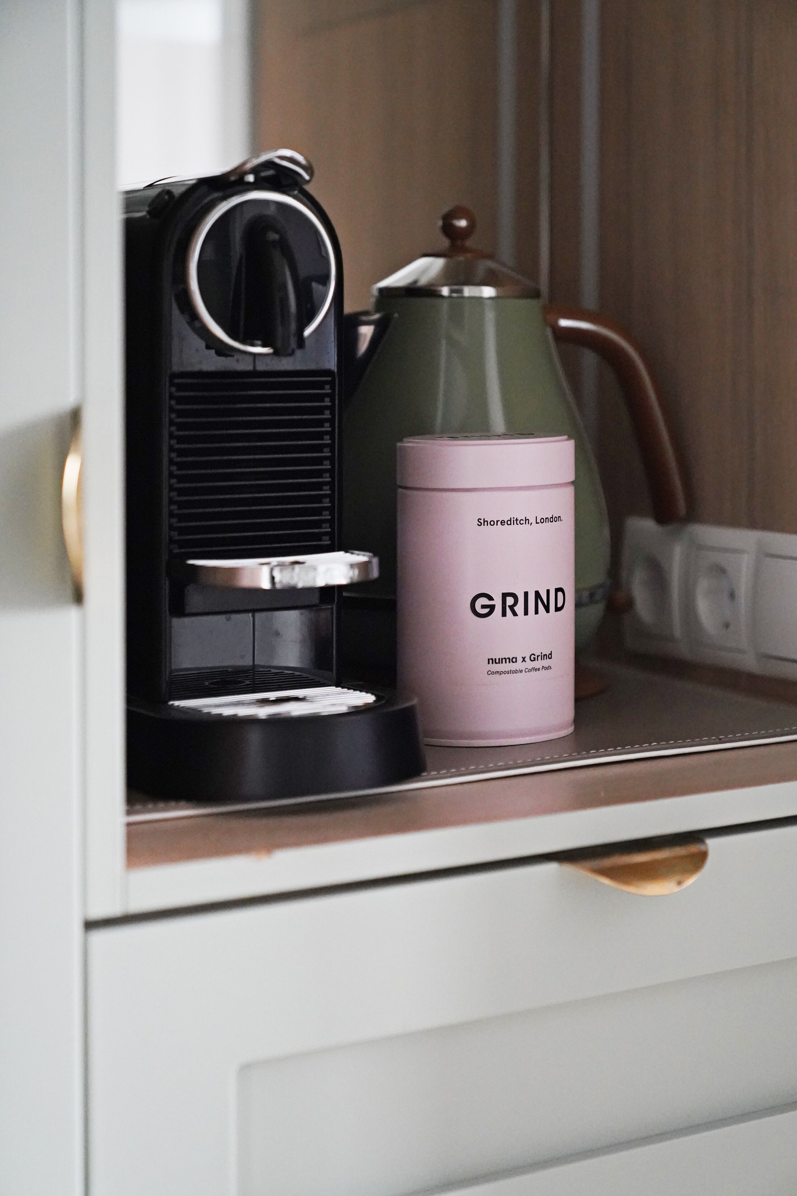 A coffee machine and a container labeled "GRIND" on a countertop.