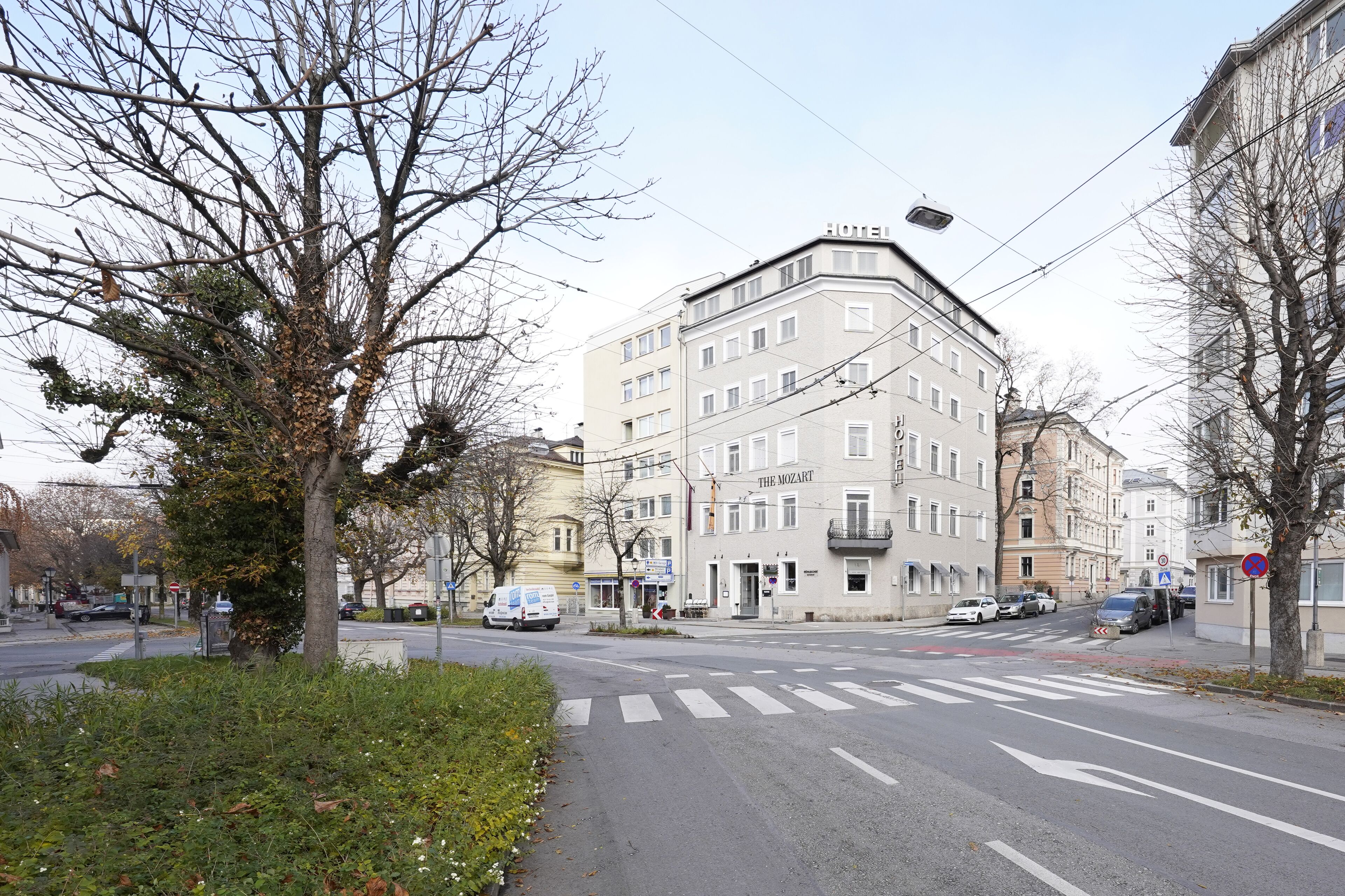 A multi-story building with a corner entrance, a crosswalk, and parked cars.