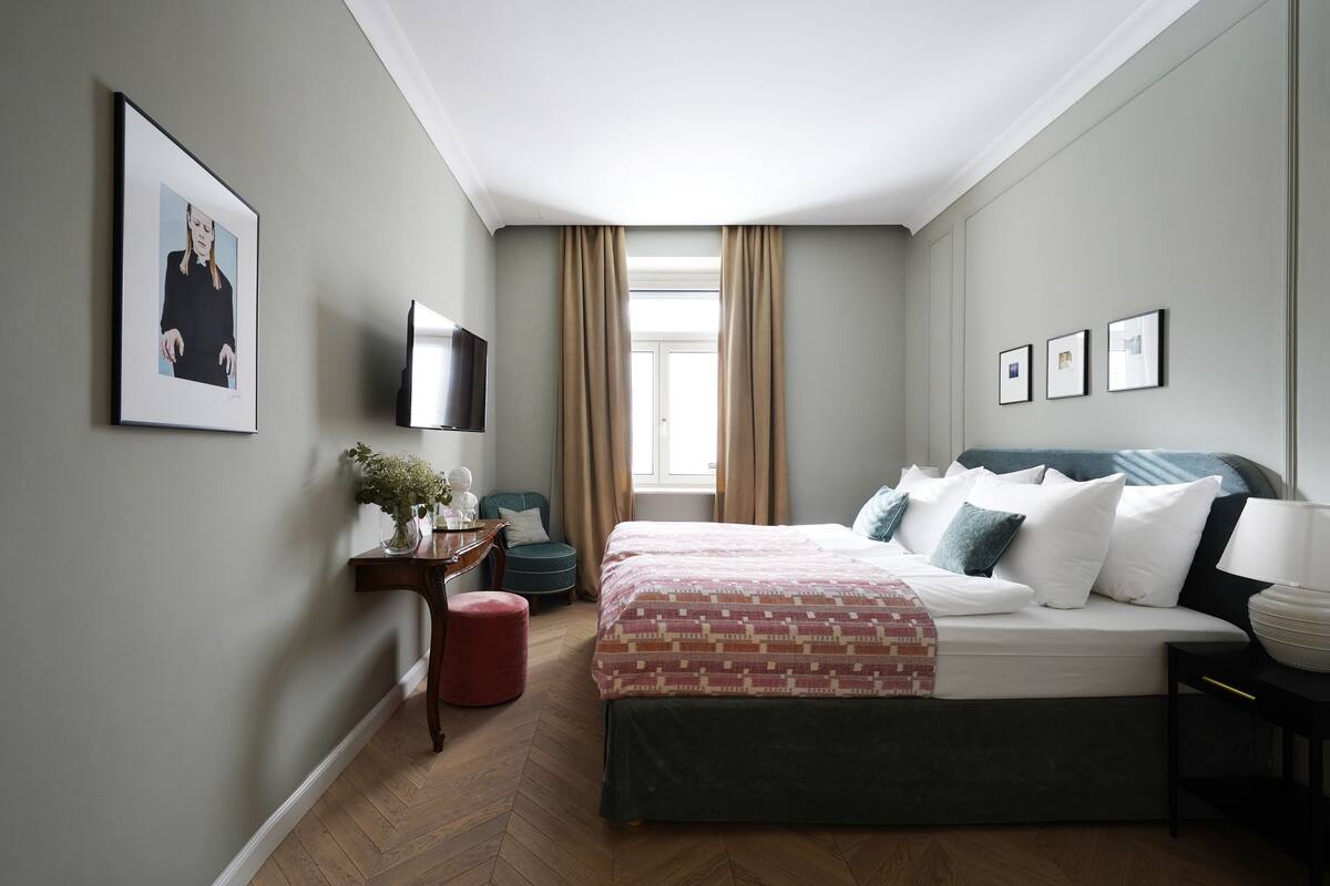 Quarto com cama, TV, escrivaninha e cadeira.