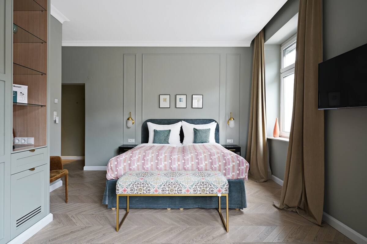 Quarto com cama, mesas de cabeceira, televisão e guarda-roupa.