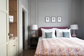 Un dormitorio con una cama, dos mesitas de noche, un armario y tres cuadros en la pared.