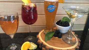 Variedad de bebidas sobre una tabla de madera con una cerveza, un cóctel rojo, un martini y una copa de vino.