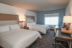 A hotel room with two beds, a desk, and a chair. There are lamps on the nightstands and a window with curtains. - Holiday Inn Cleveland-Mayfield by IHG (Mayfield)