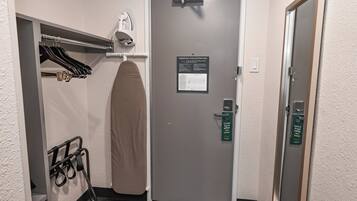 A hotel room with a grey door, a towel rack with hanging towels, and a sign indicating an emergency evacuation plan.