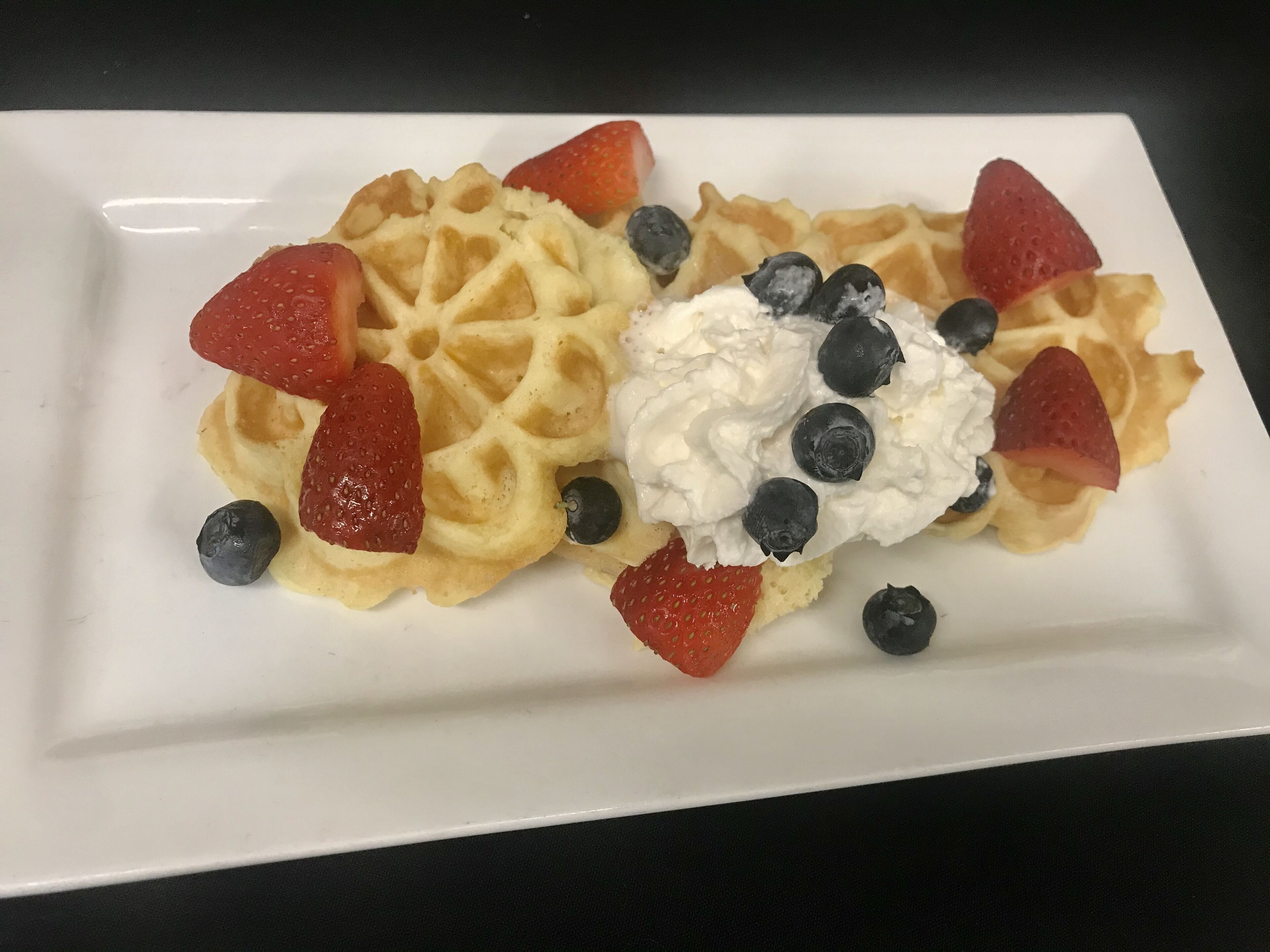 A plate with waffles, strawberries, and blueberries.