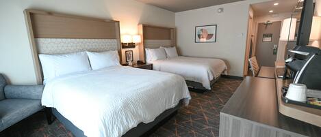 Habitación de hotel con dos camas, un escritorio y zona de estar.