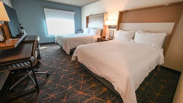 A hotel room with two beds, a desk, and a chair.