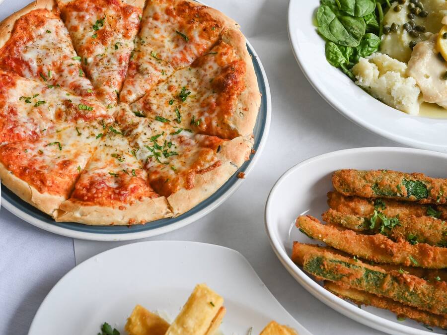 A variety of dishes including a pizza, bread, and a salad on a table.