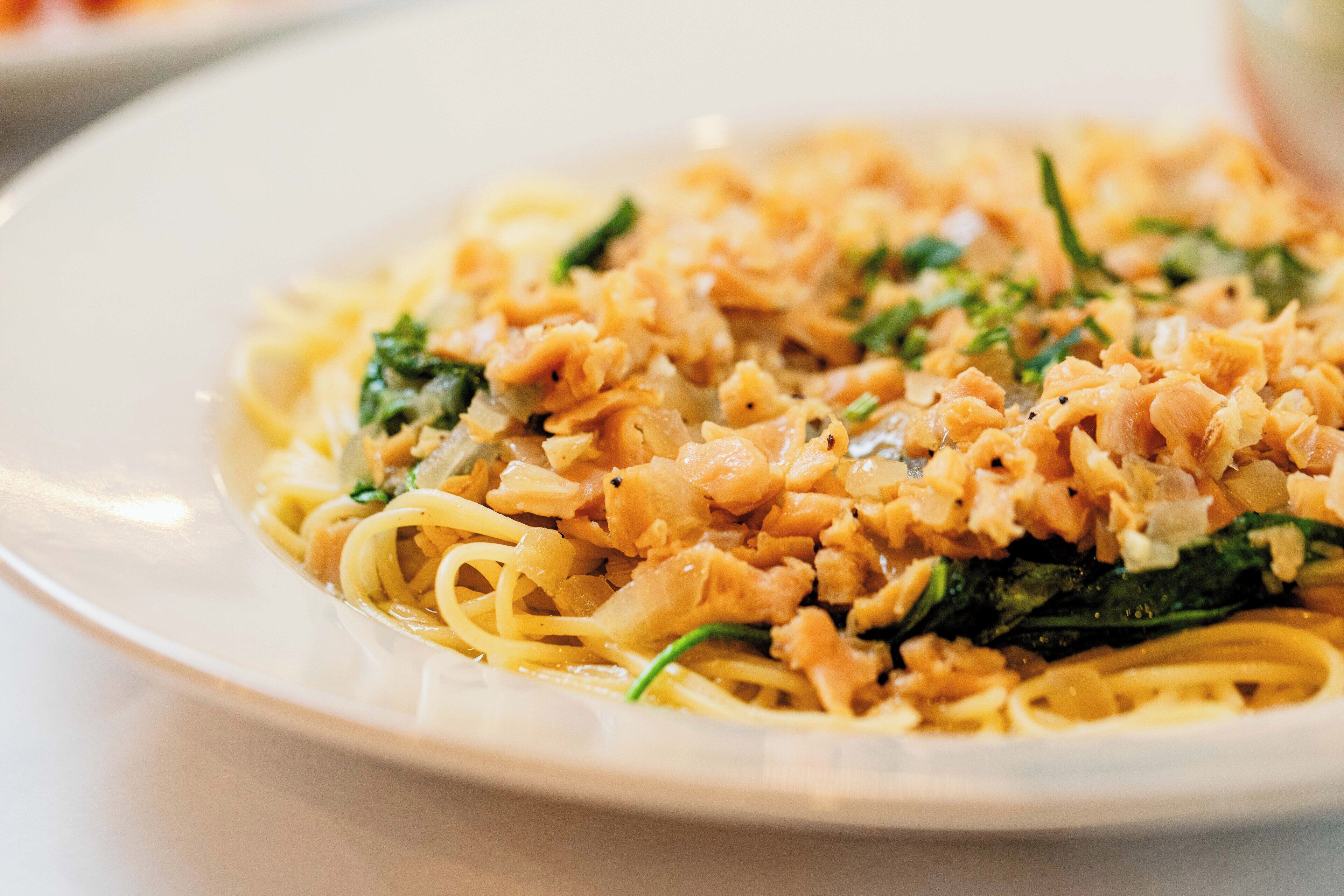 Une assiette de pâtes nappées d’une sauce crémeuse, garnie d’herbes fraîches.