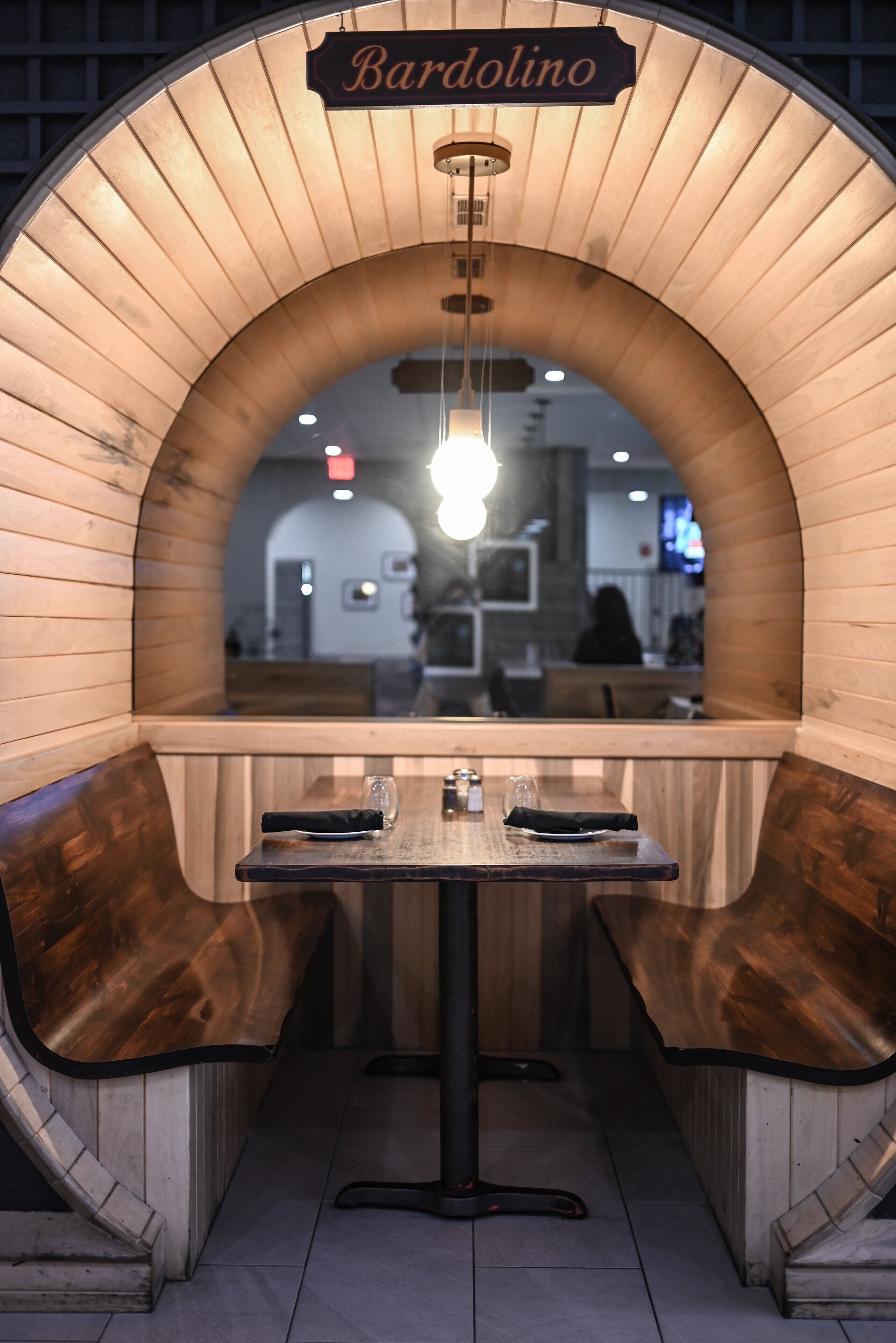 A cozy, wooden booth seating area with a sign reading "Bardolino."