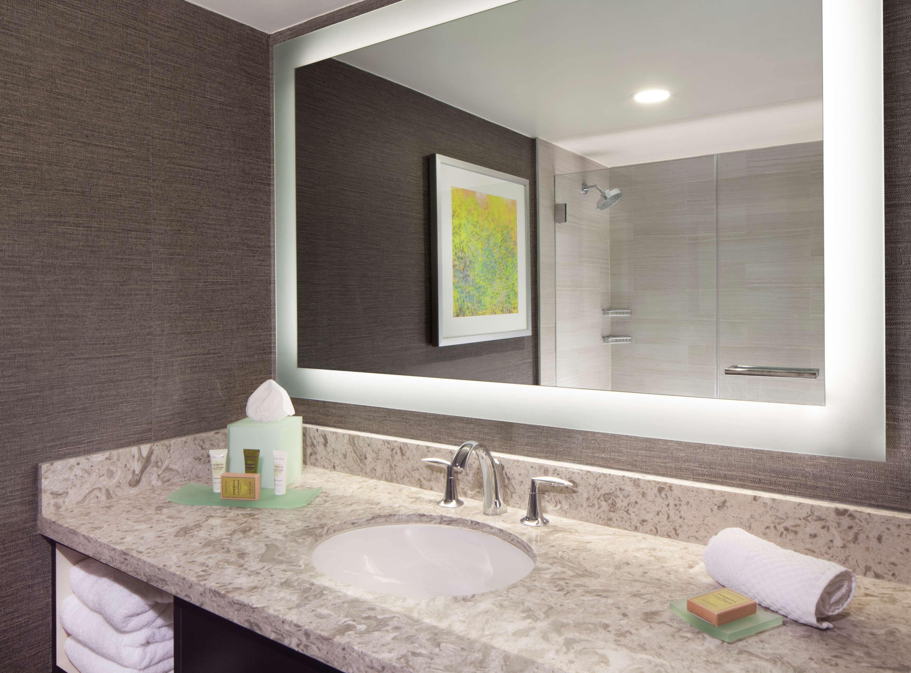 A bathroom with a marble sink, a large mirror, and a shower area.