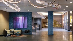 Un hall d’entrée spacieux, agrémenté d’un grand tableau abstrait, d’une cheminée et d’un espace bien éclairé avec une bibliothèque.