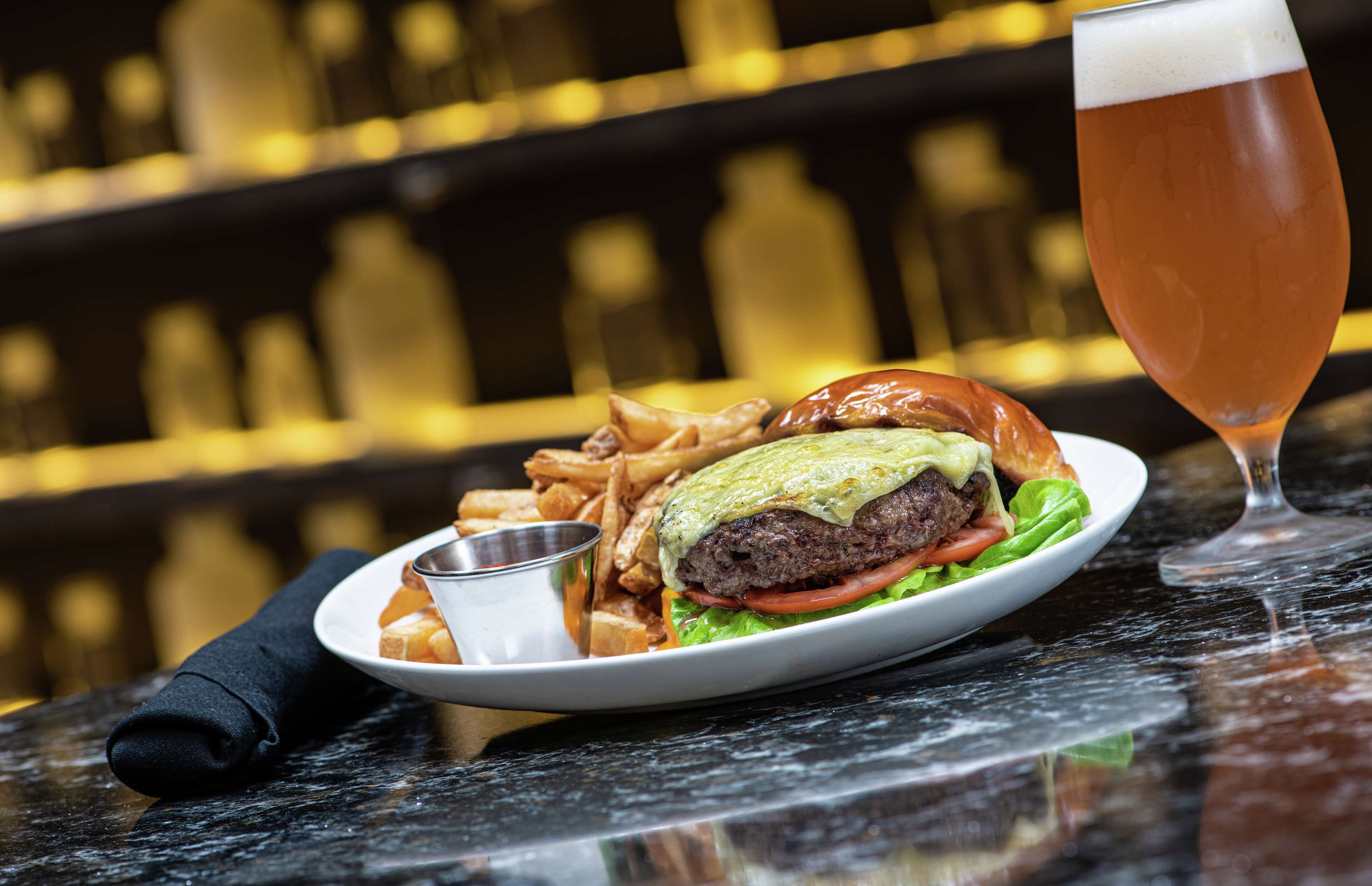 A plate with a burger, fries, and a drink on a table.