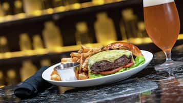 A plate with a burger, fries, and a drink on a table.
