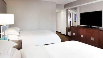 A hotel room with two beds, a TV, and a wooden dresser.