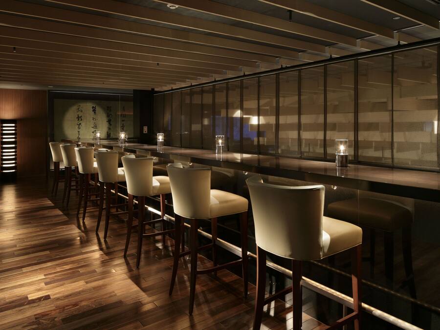 A bar area with wooden flooring and modern bar stools.