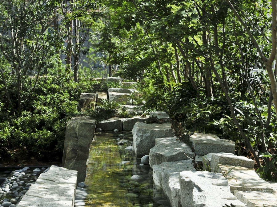 A stone pathway leading through a lush garden with a small water feature.