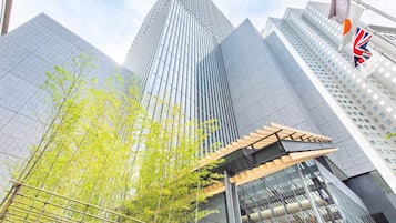 A modern building with a glass facade, a covered entrance, and a flagpole with a flag.