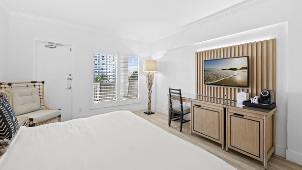 Une chambre d’hôtel comprenant un lit, un bureau avec une télévision, une chaise et une lampe.