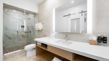 A modern bathroom with a glass-enclosed shower, a white sink, and a large mirror.