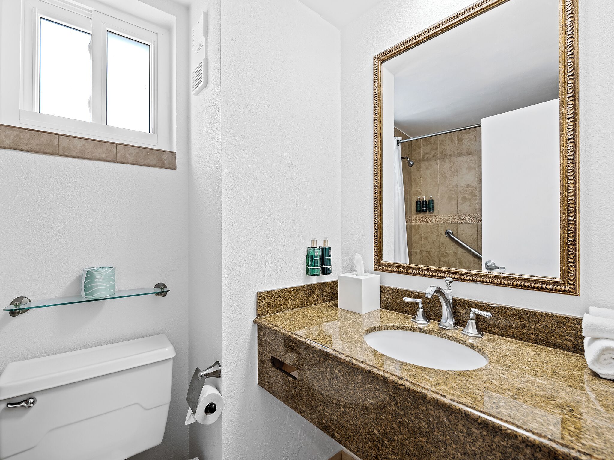 Un baño con inodoro, lavabo, espejo y ducha.