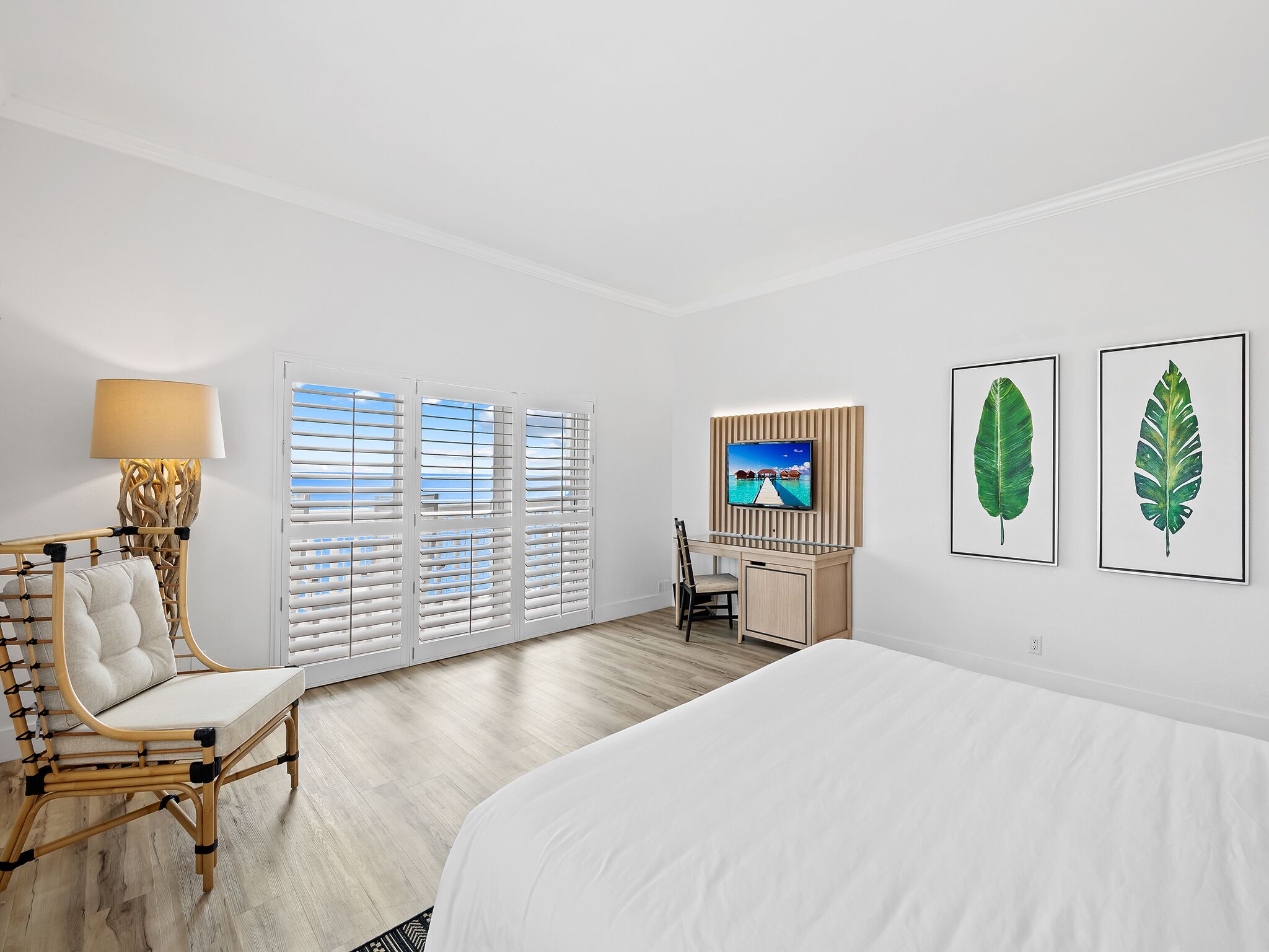 Ett hotellrum med en säng, ett skrivbord med en tv, en stol och ett fönster med persienner.
