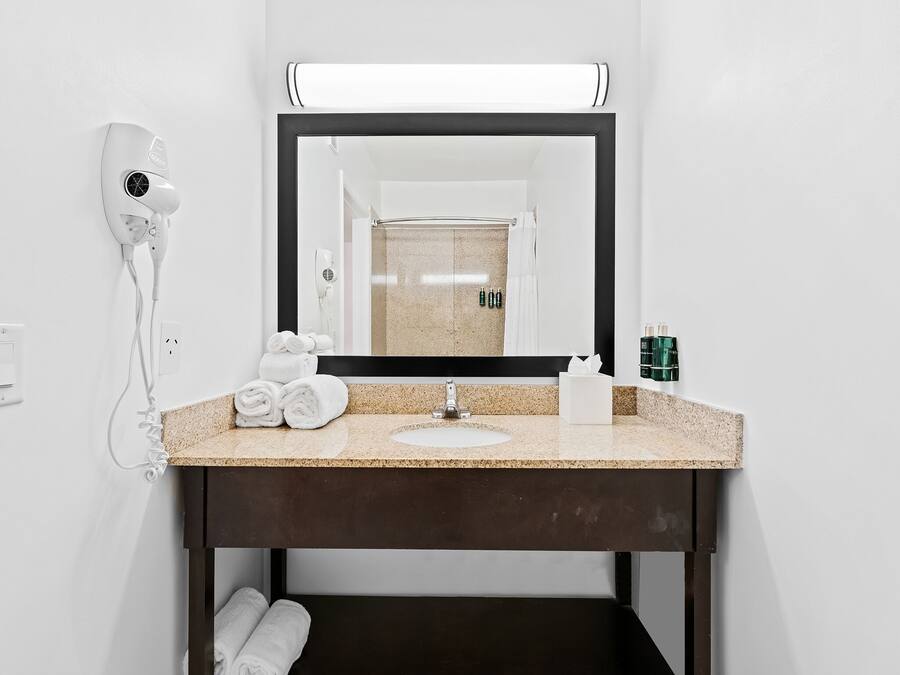 A bathroom with a sink, mirror, towel rack, and hair dryer.