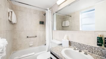 Een moderne badkamer met een bad, toilet en twee wastafels.