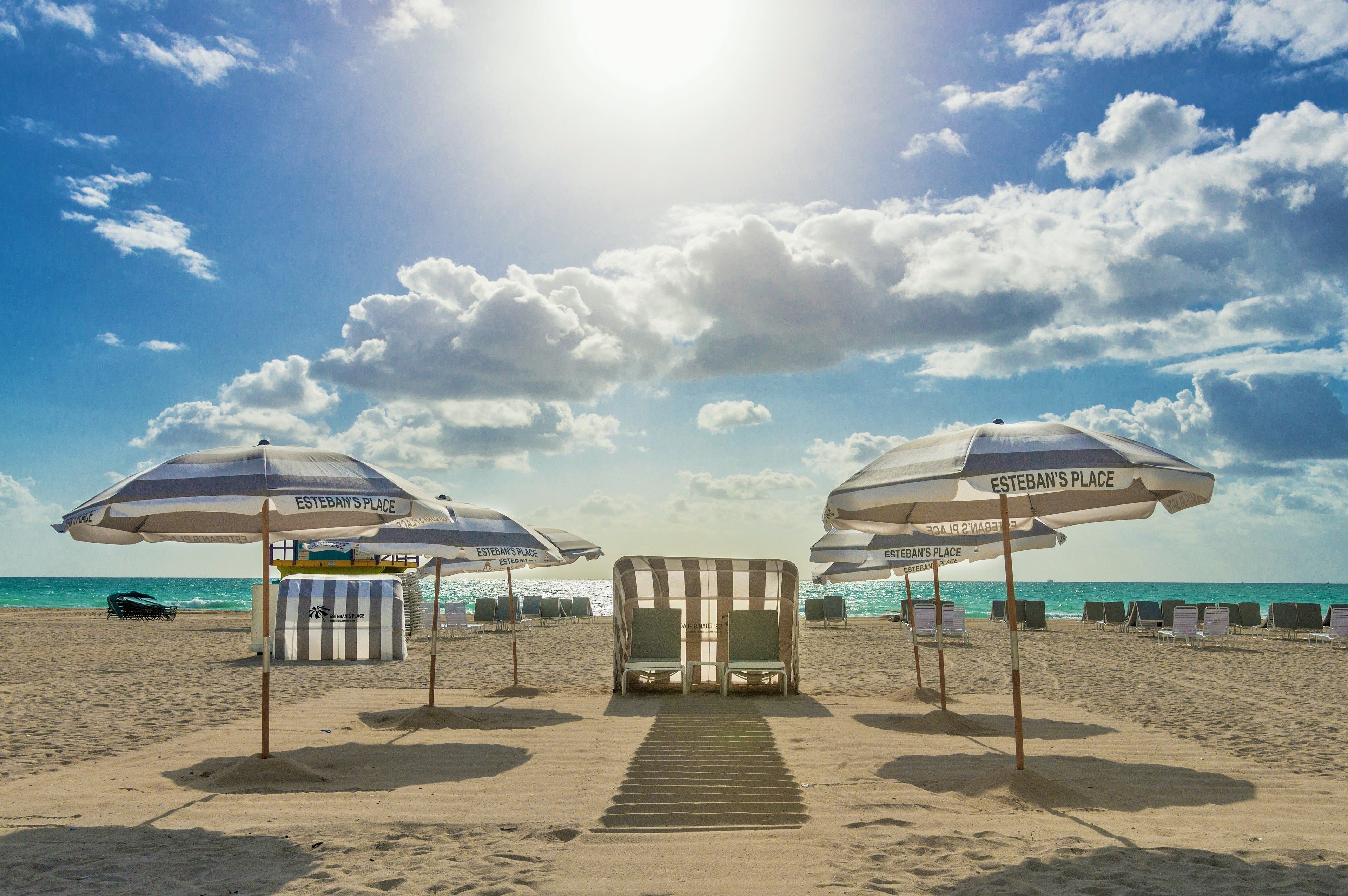 A beach with striped umbrellas labeled "Esteban's Place" and a row of beach chairs.