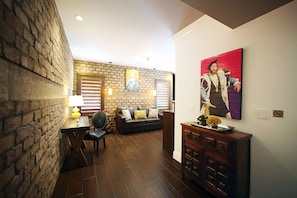 A living room with a brick wall, a wooden coffee table, a sofa, and a painting on the wall.