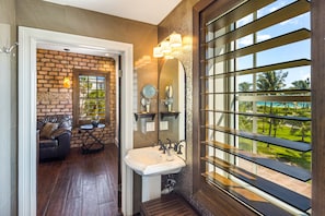 A bathroom with a large window, a sink, and a mirror.