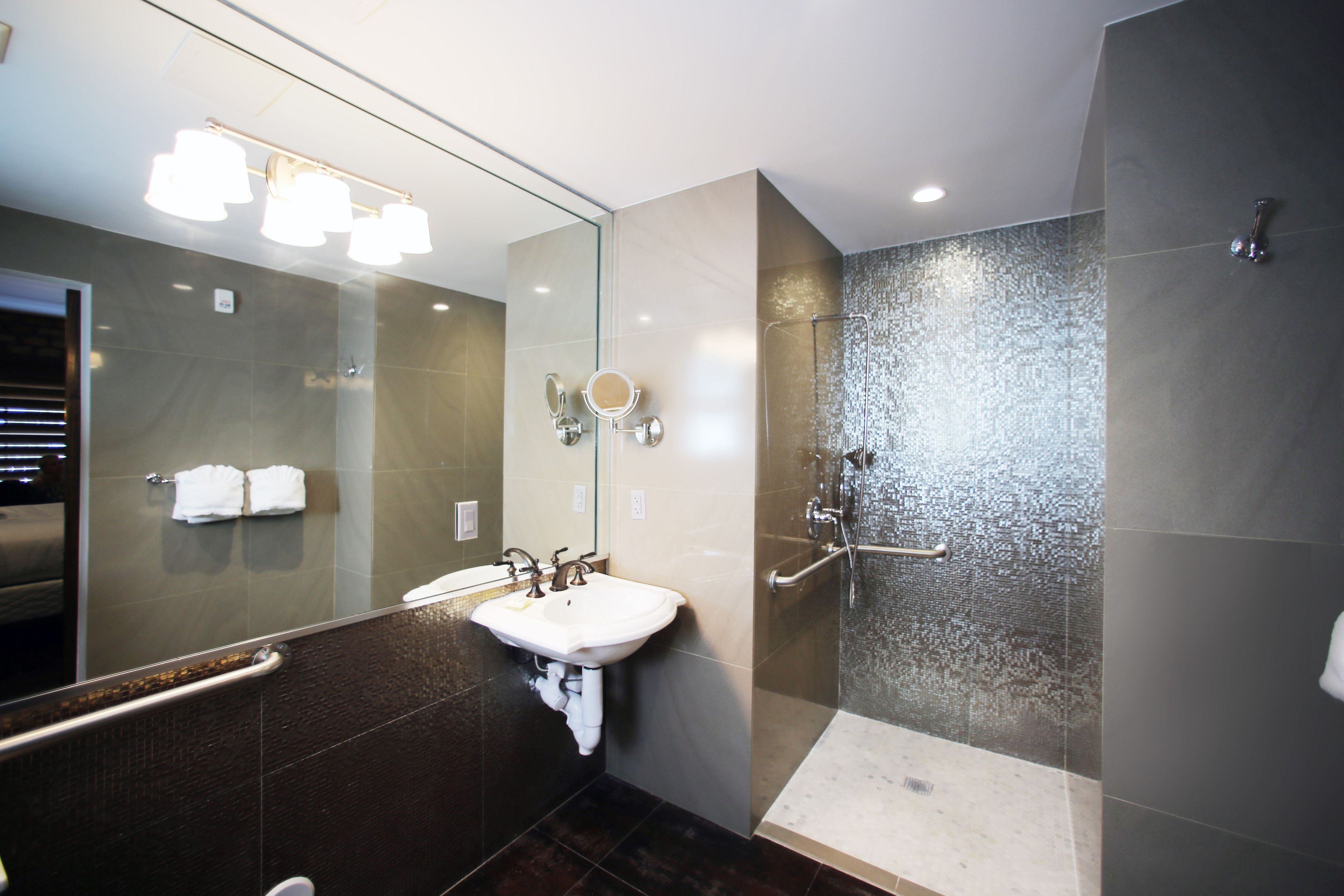 A modern bathroom with a large mirror, a sink, and a shower area.