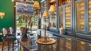 A bar area with a green wall, a chandelier, and shelves of bottles.