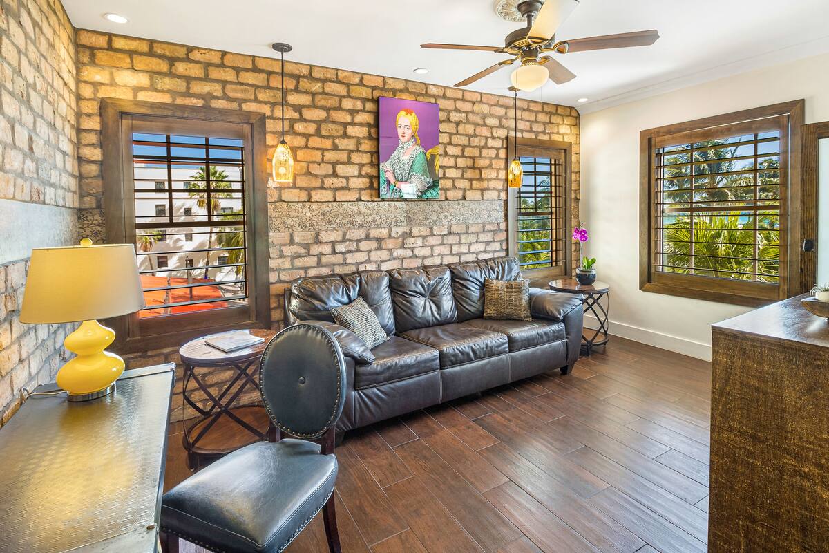 A living room with a leather sofa, a coffee table, a lamp, and a ceiling fan.
