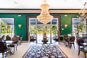 A hotel lobby with a large chandelier, green walls, and a view of palm trees through the glass doors. - Cavalier Hotel South Beach (Miami Beach)