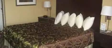 Una habitación de hotel con una cama grande, una mesita de noche y una lámpara.
