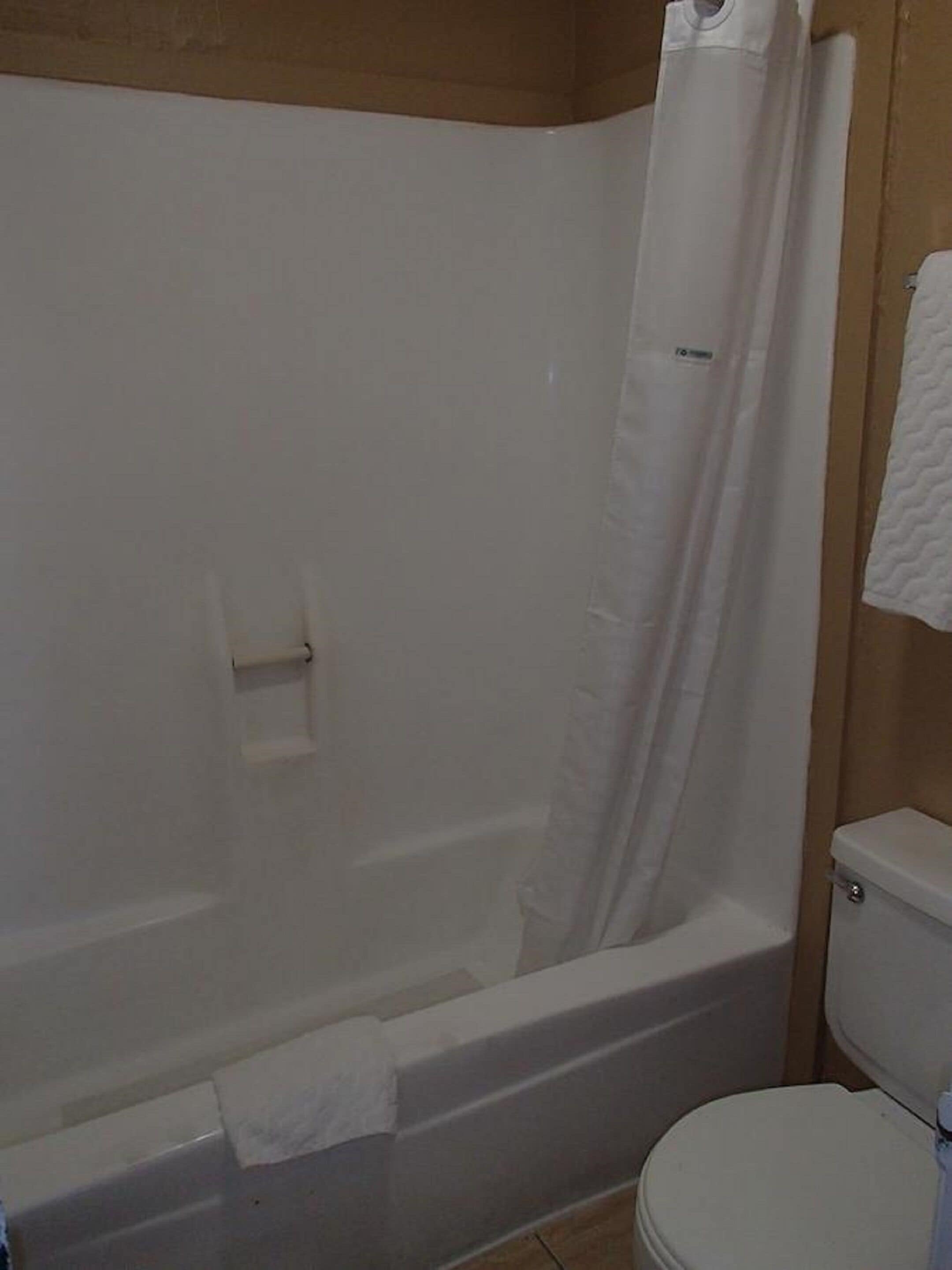 A bathroom with a bathtub, toilet, and a towel hanging on the wall.