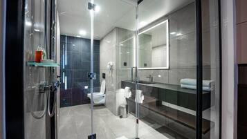 A modern bathroom with a glass-enclosed shower, a toilet, and a vanity with a mirror.