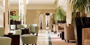 Relax in our inviting lobby, featuring plush seating, lush greenery, and a striking sculpture.