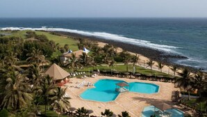 Un resort con un amplio espacio de piscina, playa y vistas al océano.