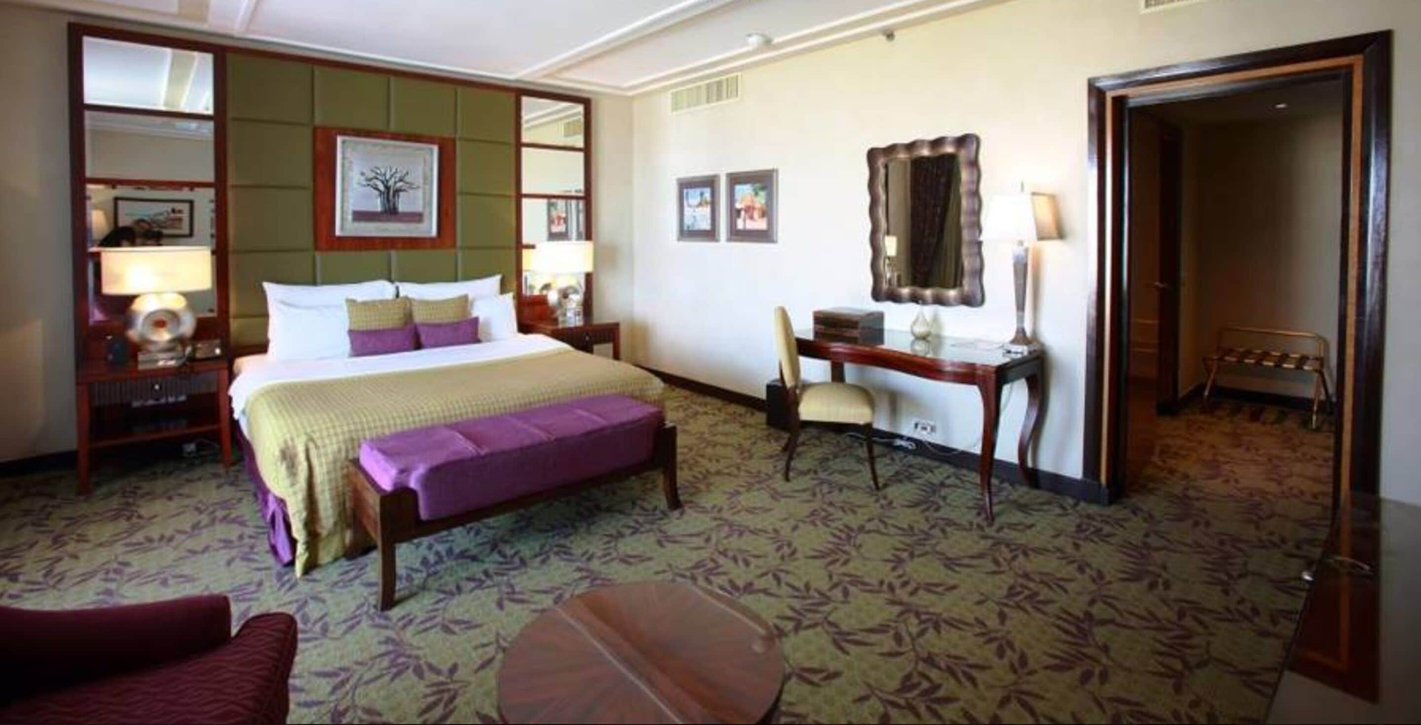 Une chambre d’hôtel comprenant un lit, un bureau, une chaise, une petite table et un miroir.