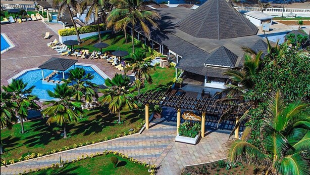 Un resort con piscina, sillones de descanso, palmeras y un pabellón.