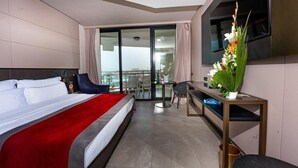 Una habitación de hotel moderna con una cama grande, un escritorio, una silla y un balcón con vistas.