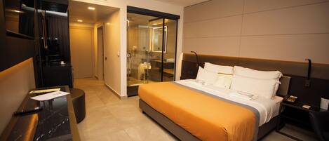 A hotel room with a bed, a desk, a chair, a mirror, and a bathroom visible through an open door.